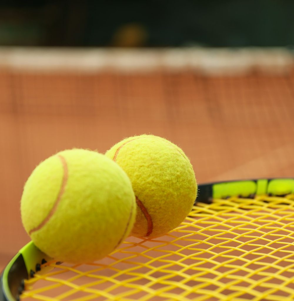Tennis racquet with tennis balls against clay court